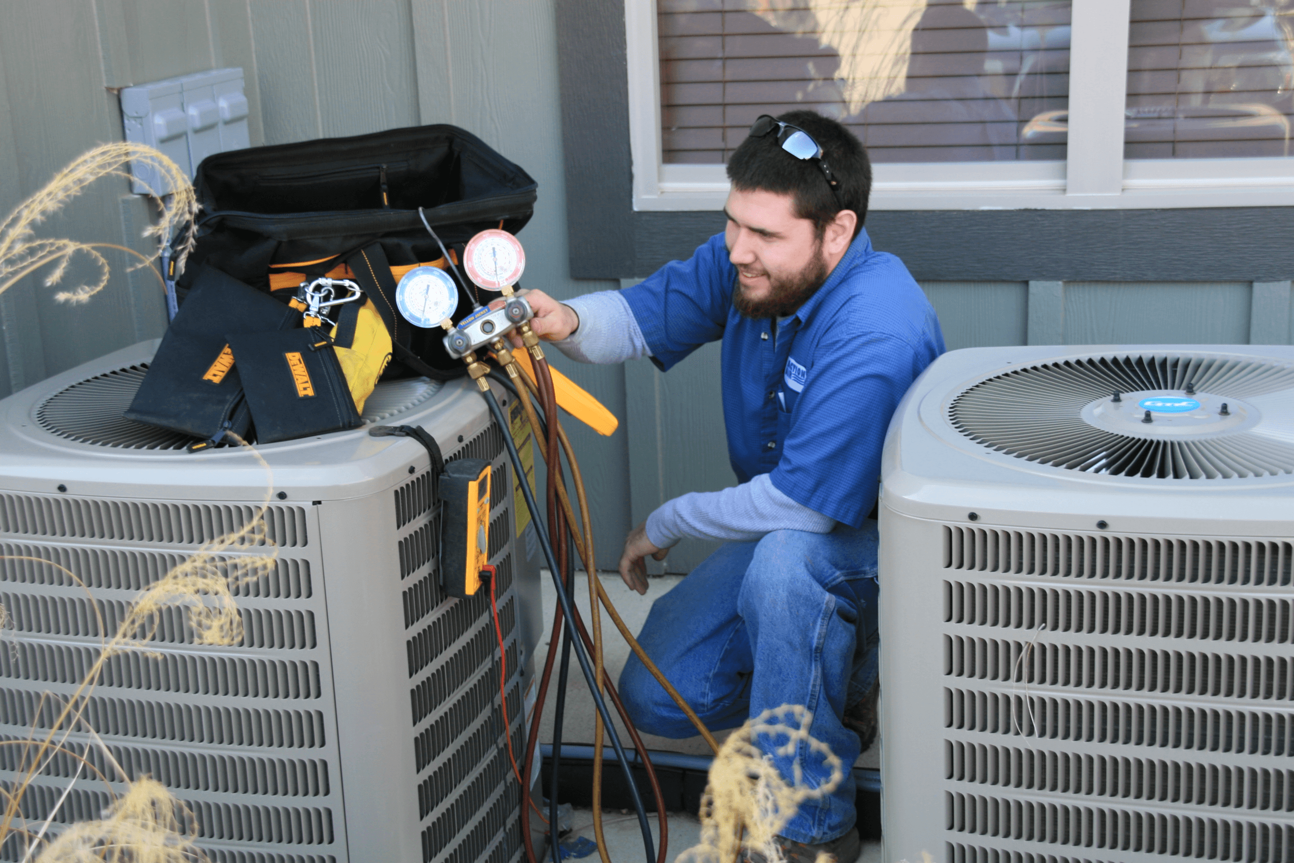 HVAC technician using gauges to diagnose air conditioning system performance