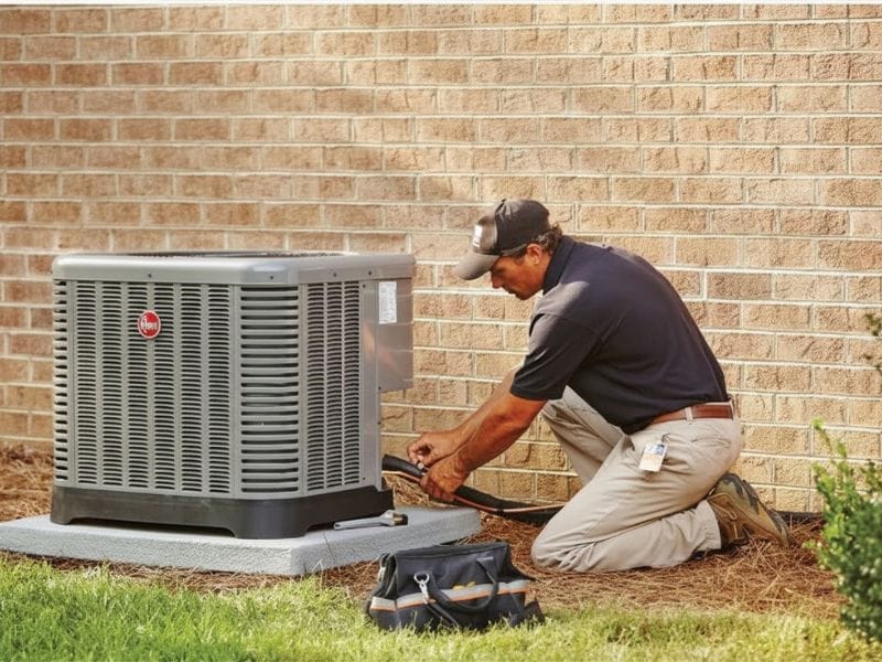 Technician performing AC repair and maintenance on outdoor air conditioning unit